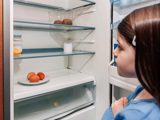 Child looking into a near empty fridge.