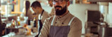 Male restaurant owner with glasses and beard smiling with arms crossed while standing in an industrial kitchen
