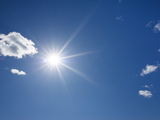 Sun against a blue sky with few clouds.