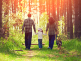 Family walking in forest with their dog.