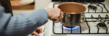 Person holding a pot of boiling water on a stove