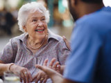 Senior woman smiling to a worker at long term care home.