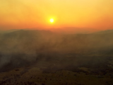 Sun and haze from wild fires over hills.