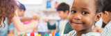 Little girl at daycare smiling at camera while doing crafts