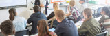 Students sitting in a classroom with teacher giving a lecture.