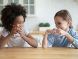 Two young girls sitting at table drinking water