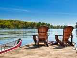 Two Adirondack chairs sitting on a dock in the summertime